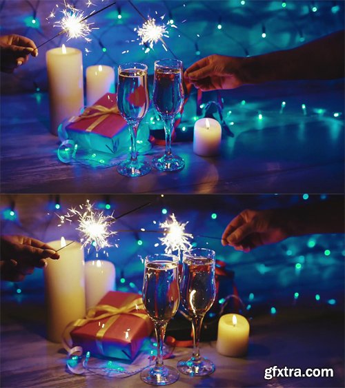 Hands with sparklers on the background of the Christmas decor, candles, gifts and glasses of champagne Hands with sparklers on the background of the Christmas decor, candles, gifts and glasses of champagne