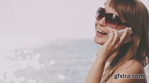 Beautiful young woman in bikini talking smart phone on the sea beach sunny summer by the sea