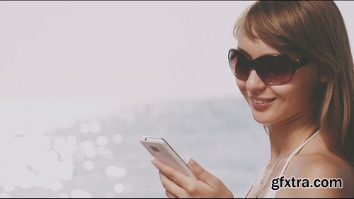 Beautiful young woman in bikini talking smart phone on the sea beach sunny summer by the sea slow