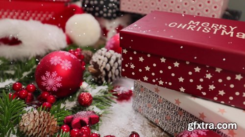 Red Christmas holiday gift box with falling snow and colorful decorated pine tree in background Red Christmas holiday gift box with falling snow and colorful decorated pine tree in background