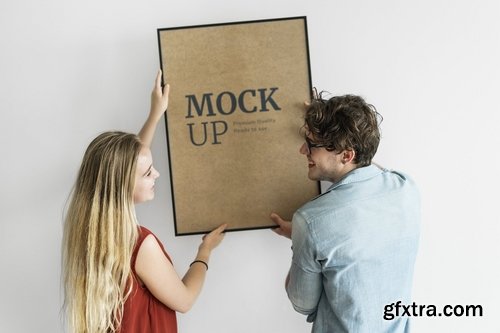 Couple hanging a photo frame mockup on white wall