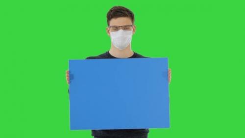 Videohive - Young Man in Medical Mask Showing and Displaying Placard on a Green Screen, Chroma Key