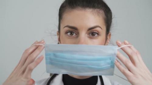 Videohive - Young Female Doctor Puts Face Mask on Mouth and Nose. Protective Measures Against COVID-19, Close