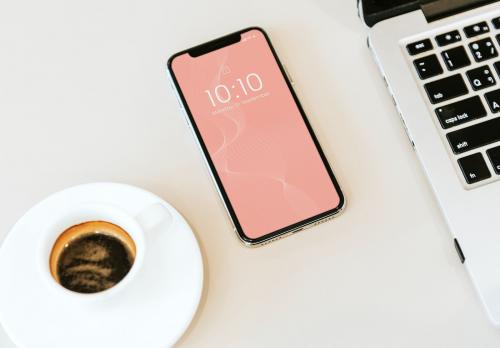 Phone mockup on white table with a laptop and a coffee cup - 561077