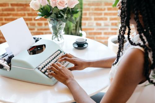 Woman typing on retro light blue pastel typewriter - 2030293