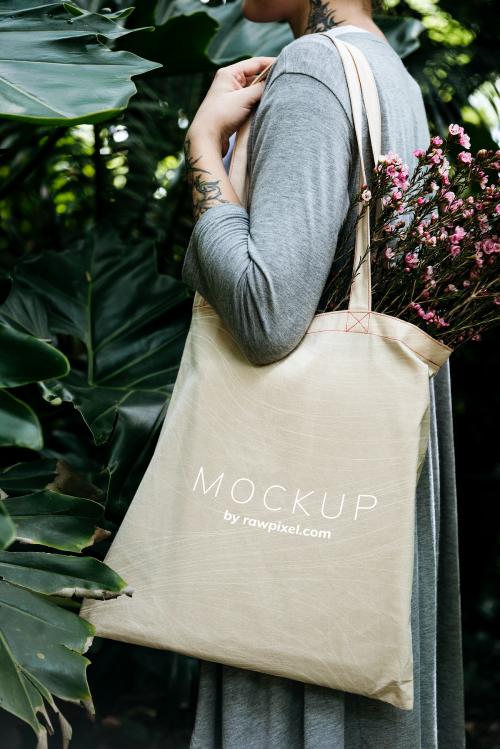 Woman carrying a tote bag mockup with flowers - 502966