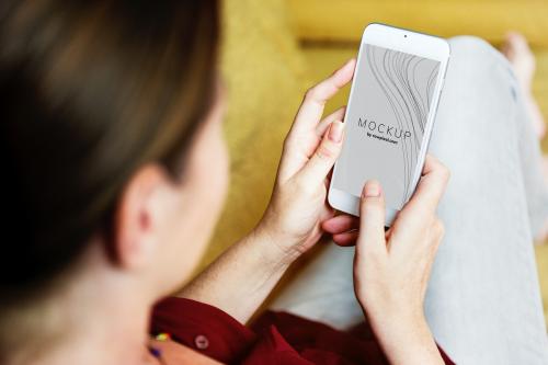 Woman sitting on a couch using a smartphone mockup - 502988