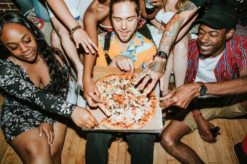 Group of diverse friends enjoying pizza at a party - 2097415
