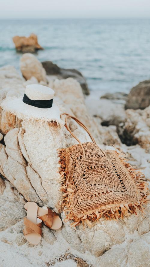 Straw hat and a woven bag on a rocky beach mobile phone wallpaper - 1228548