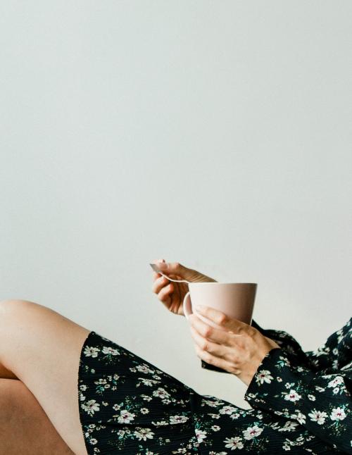 Woman sitting by a white wall with a cup of tea - 1226400