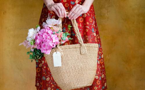 Woman carrying flowers in a wicker bag - 1207158