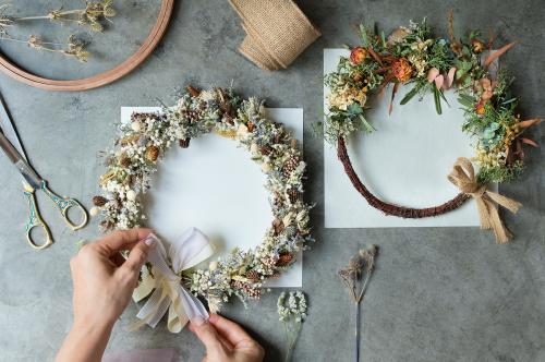 Woman tying a ribbon on a floral wreath - 1207613