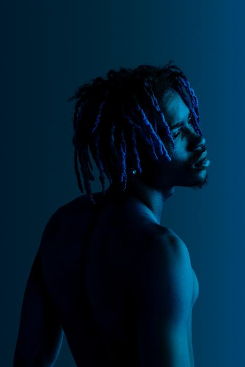 Black man posing by a blue background - 1213844