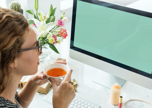 Woman drinking tea and staring at a mockup computer screen - 5206