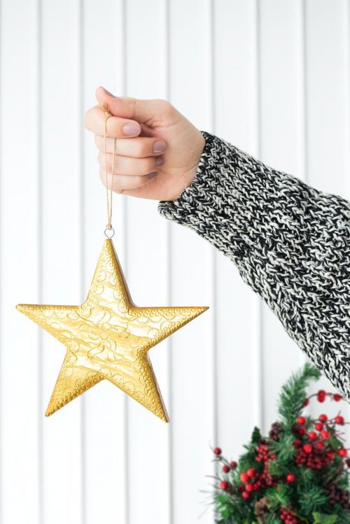 Woman holding a glittery gold star Christmas ornament mockup - 1231716