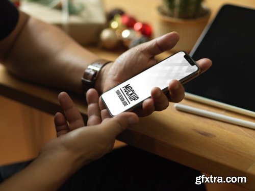 Hand holding smartphone mockup and christmas decorations