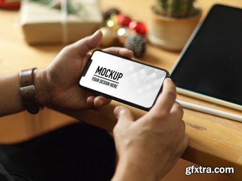 Hand holding smartphone mockup and christmas decorations