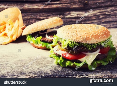 Tasty burgers with bacon, cheese sauce and potatoes - Stock Photos