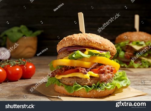Tasty burgers with bacon, cheese sauce and potatoes - Stock Photos