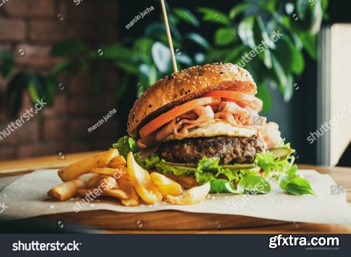 Tasty burgers with bacon, cheese sauce and potatoes - Stock Photos