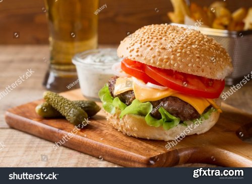 Tasty burgers with bacon, cheese sauce and potatoes - Stock Photos