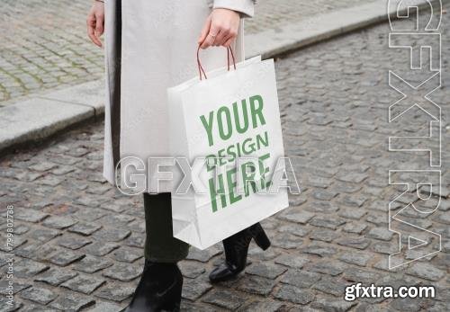 Mockup of woman with customizable paper shopping bag 799802738