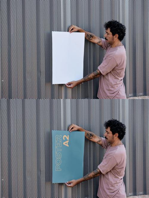 Man Holding a Vertical Poster Mockup on a Wall